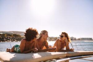 How long does it take to tan - three friends with tanned skin relaxing on a boat in the sun