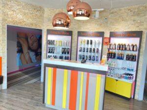 The Tanning Shop reception desk with Time to Shine product displays tanning lotion shelves and copper pendant lights