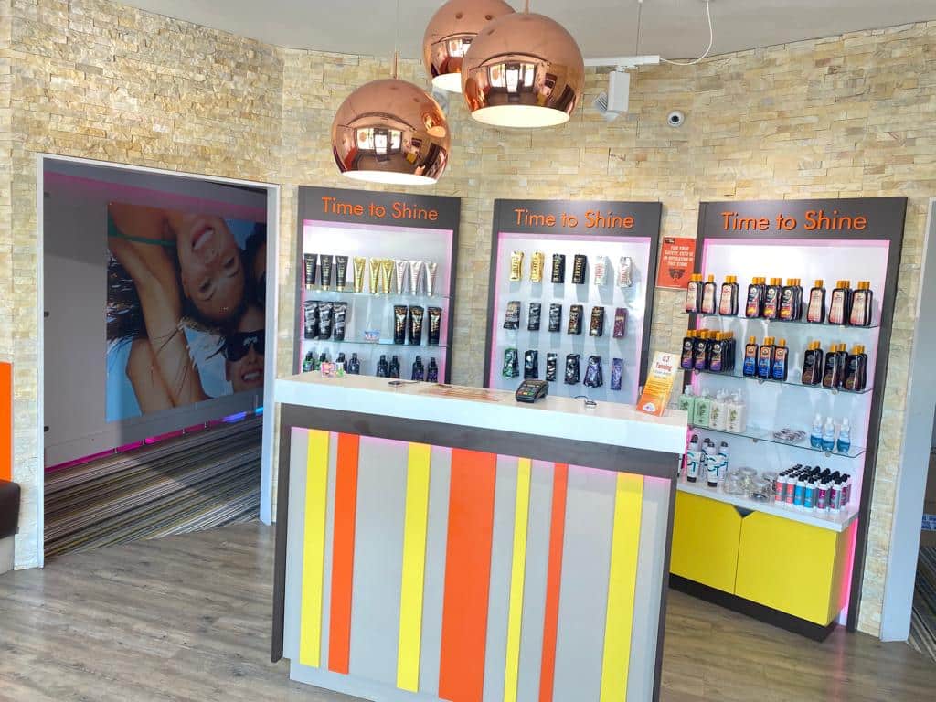 The Tanning Shop reception desk with Time to Shine product displays tanning lotion shelves and copper pendant lights