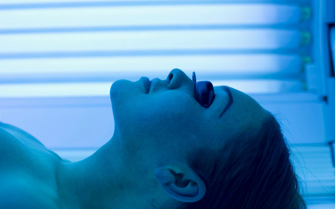 Woman relaxing in UV sunbed tanning session with blue light at The Tanning Shop UK