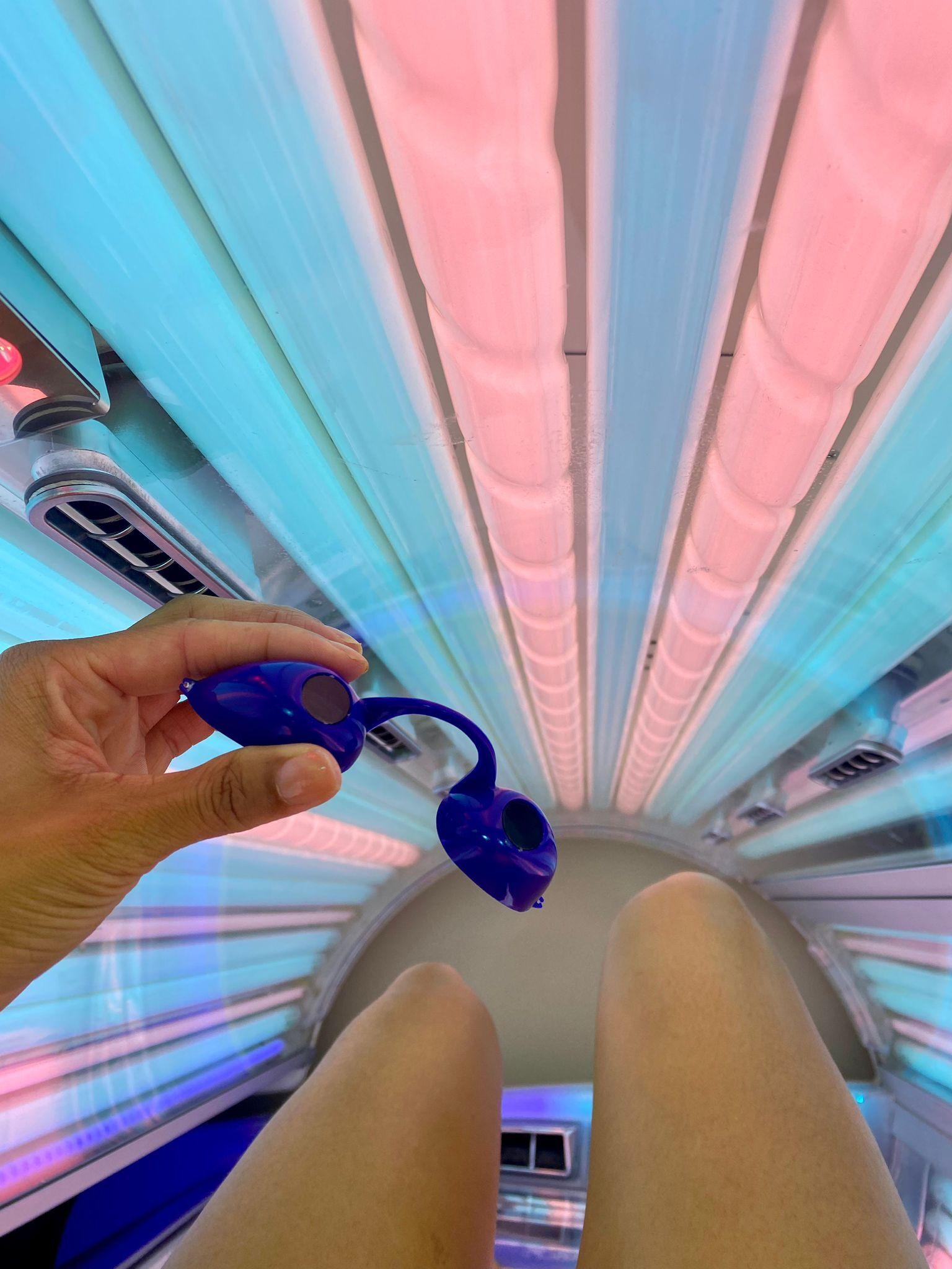 Importance of eye protection on sunbeds - person holding protective UV goggles inside a sunbed at The Tanning Shop UK