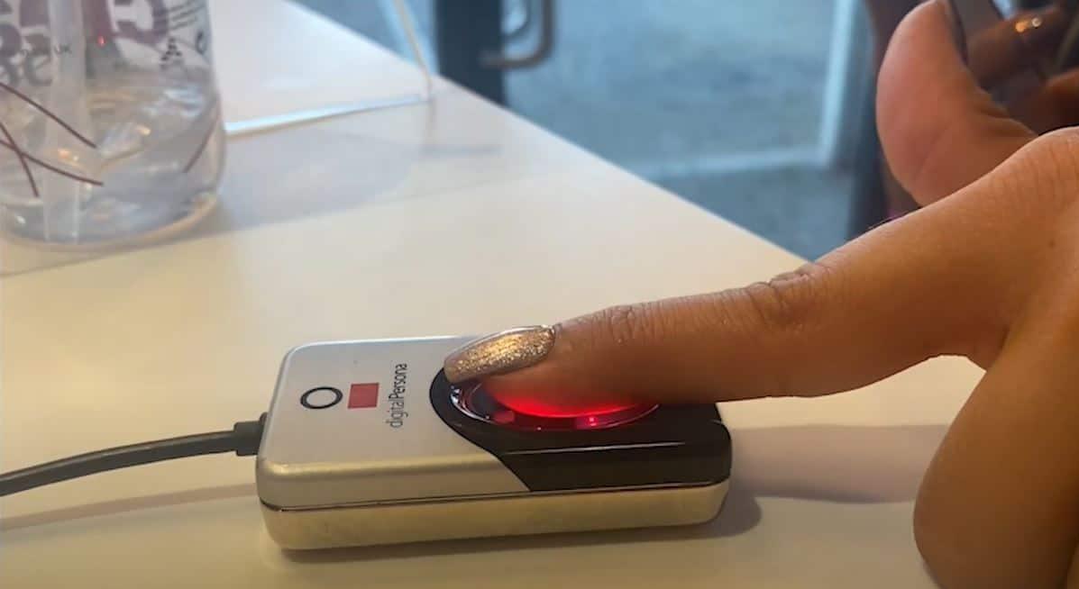 Customer using fingerprint scanner biometric check-in system at The Tanning Shop UK tanning salon