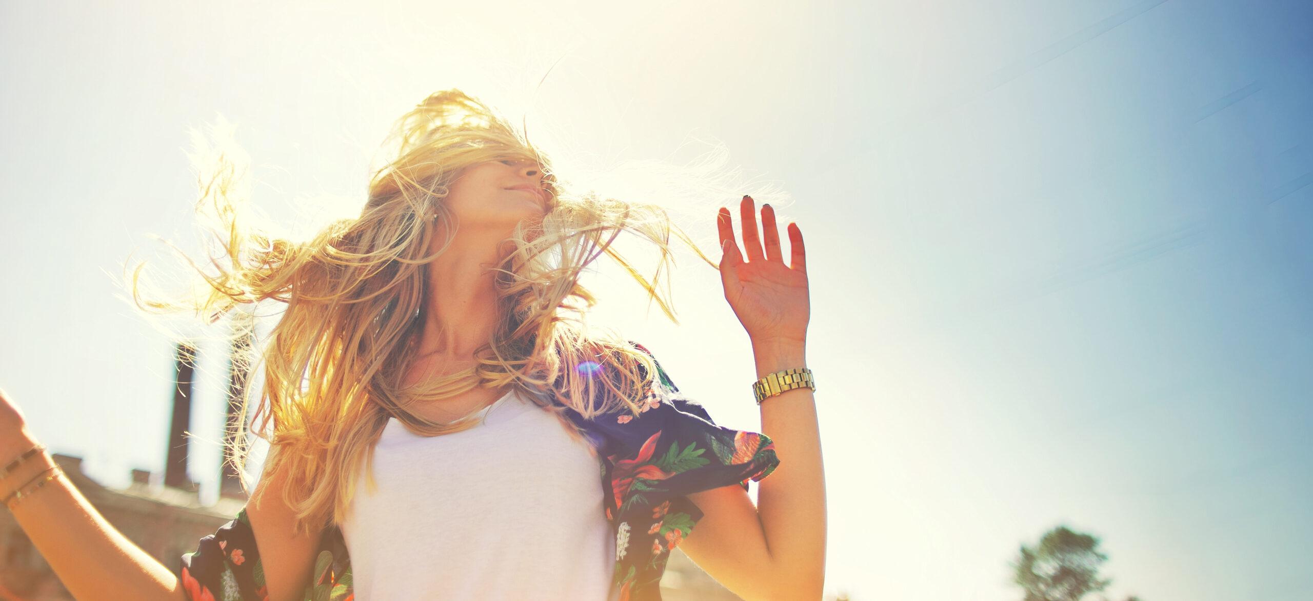 Happy young woman with sun-kissed glowing skin enjoying sunlight outdoors