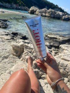 Sunbed tips for beginners - woman holding Australian Gold HOT! tanning lotion at beach The Tanning Shop UK