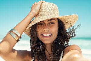 Teeth whitening service at The Tanning Shop UK - woman with bright white smile and glowing tan at beach