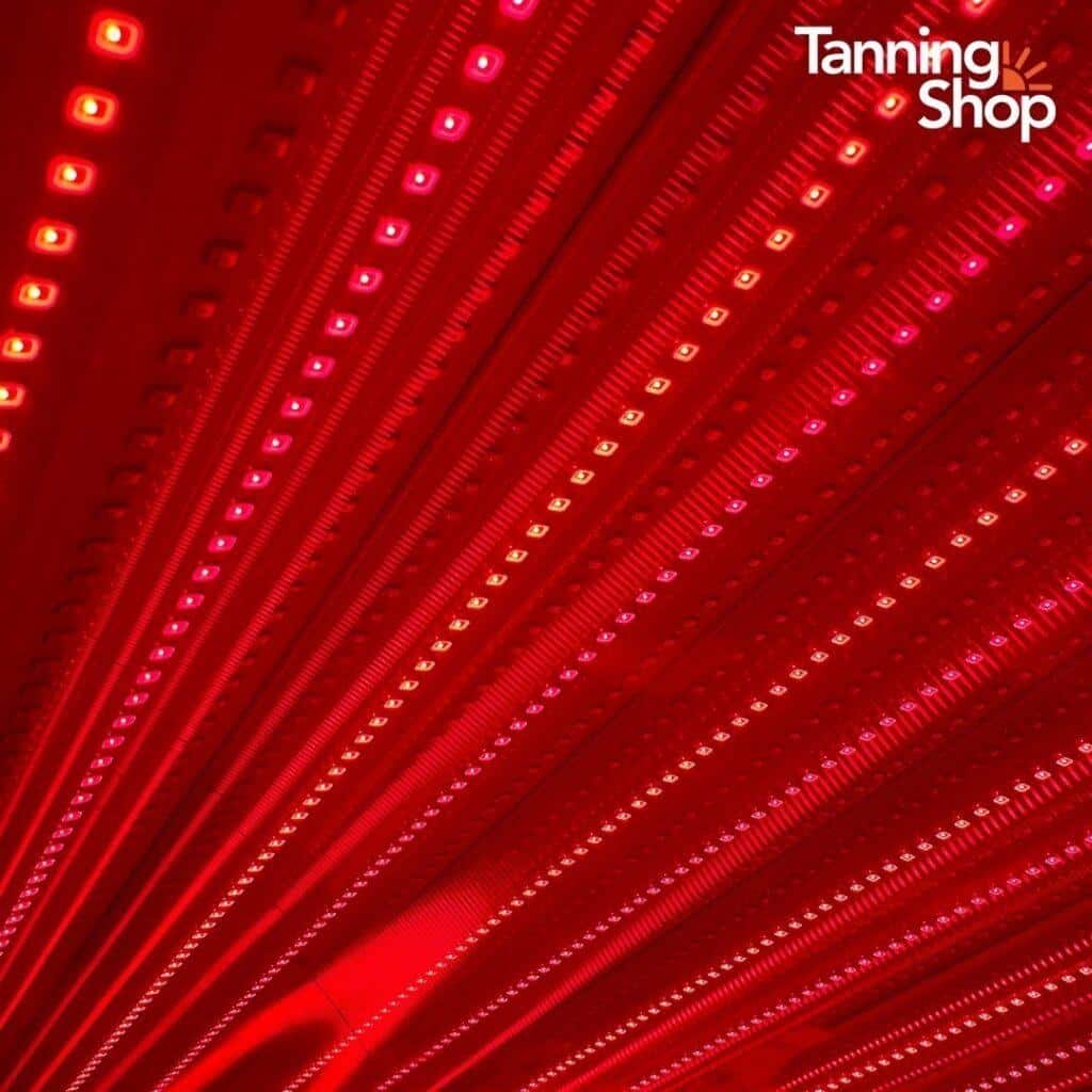 Close-up of red and pink LED lights in diagonal rows inside a Tanning Shop tanning bed canopy, showcasing red light therapy technology.