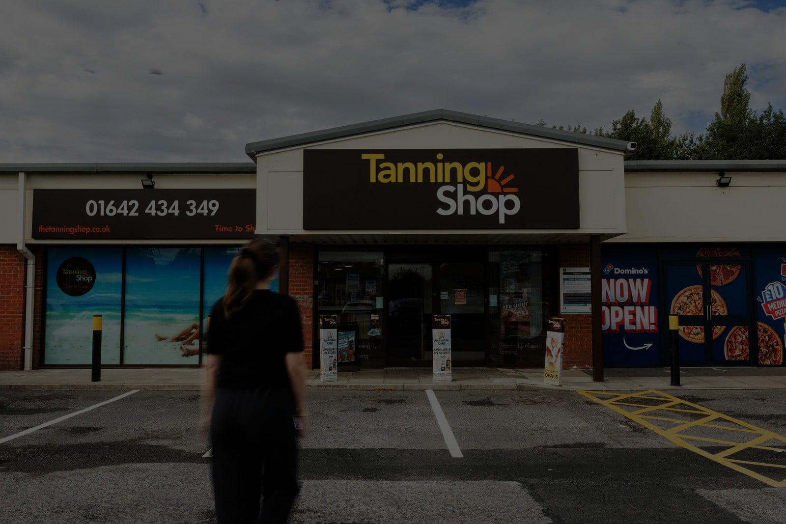 The Tanning Shop storefront with signage showing the phone number 01642 434 349 and a person walking towards the entrance