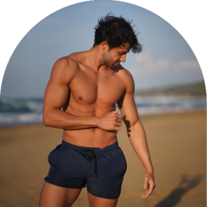 Tanned man walking on the beach showcasing natural-looking spray tan results at The Tanning Shop UK