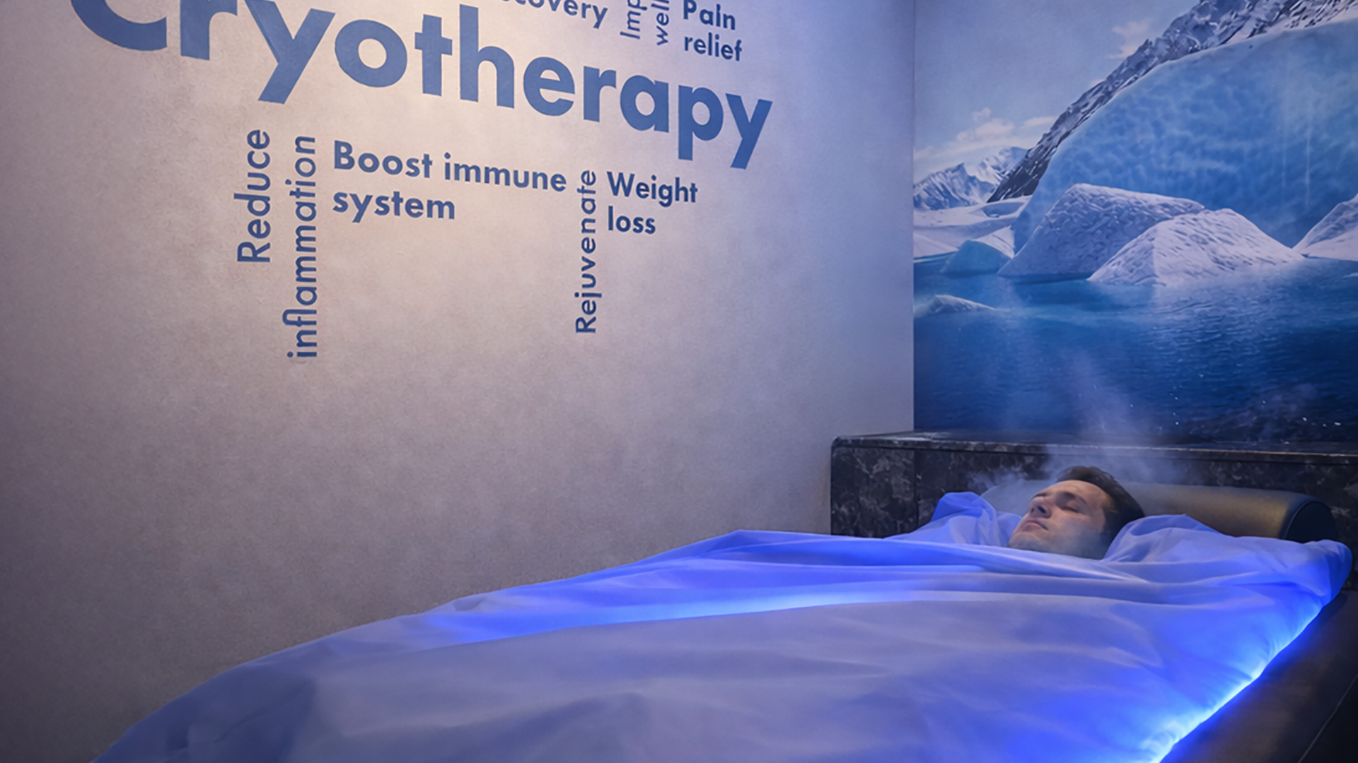 Man relaxing in a Zerobody cryotherapy bed surrounded by cold mist, with wall text highlighting benefits including reducing inflammation, pain relief, and immune system boost at The Tanning Shop UK
