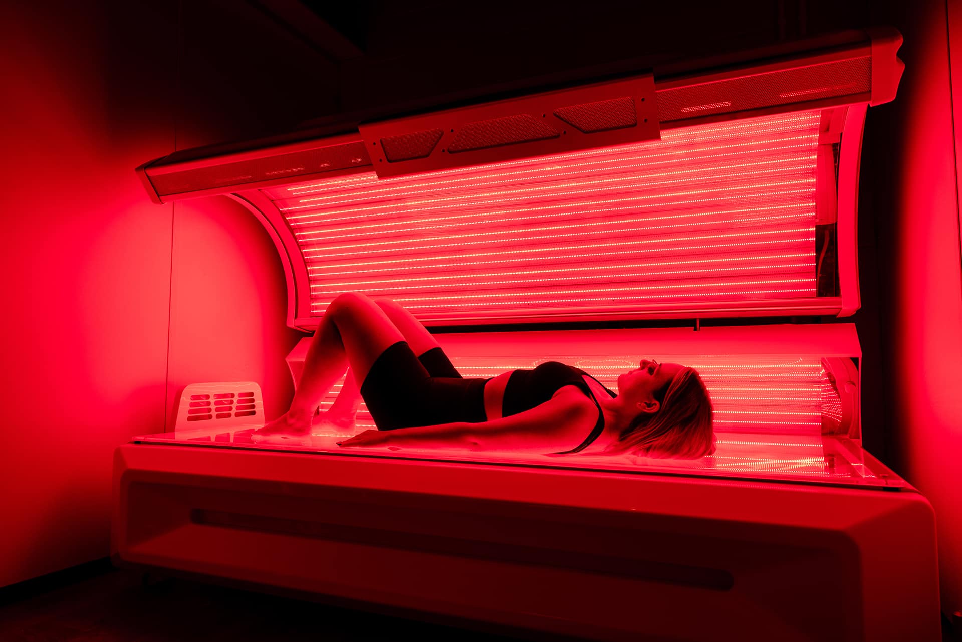 Woman lying in a full-body red light therapy bed during a skin rejuvenation and wellness session at The Tanning Shop UK