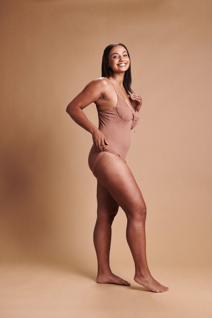 Smiling woman in swimwear with an even, natural-looking tan – WellFit skincare and Tanning Shop spray tan combined.