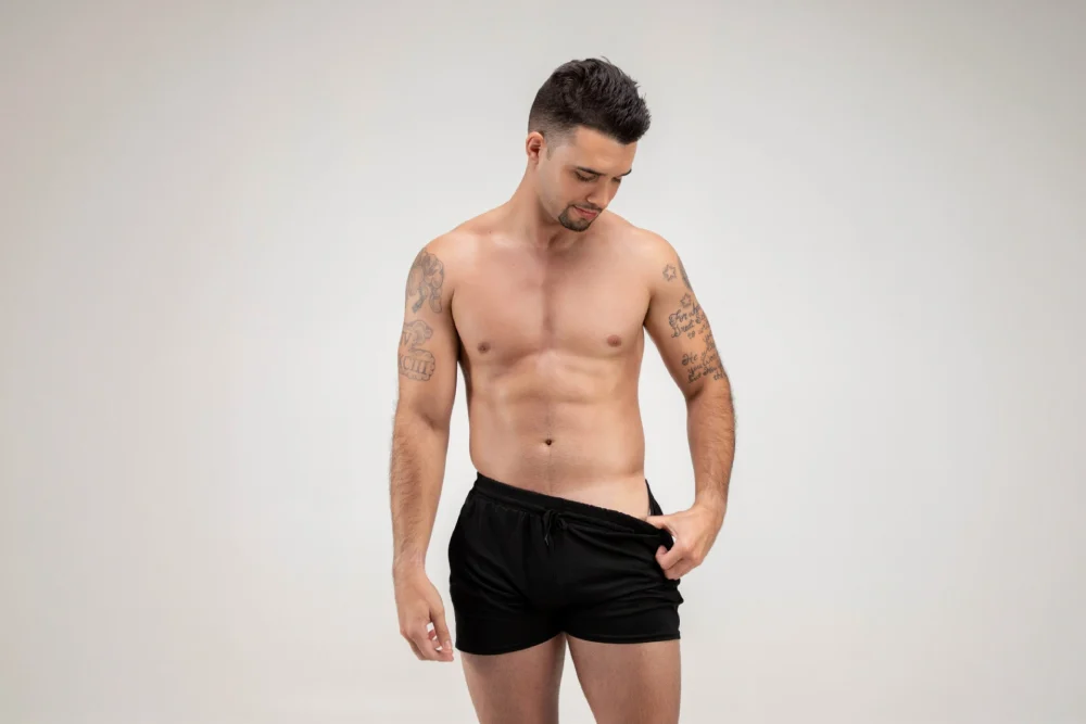 A man in black swimming trunks showing a tan line created by the Norvell clear spray tan at The Tanning Shop UK.
