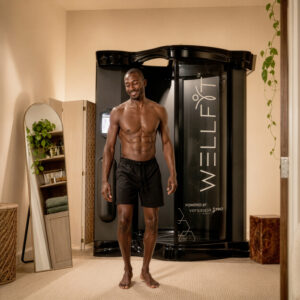 Smiling man stepping out of a VersaSpa WellFit spray booth following a full-body skincare treatment. Smiling man stepping out of a VersaSpa WellFit spray booth following a full-body skincare treatment.